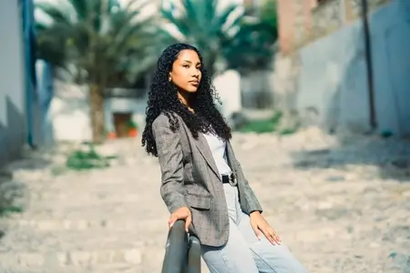 A Chic Young Woman Confidently Posing in a Lively Urban Setting Surrounded by Palms