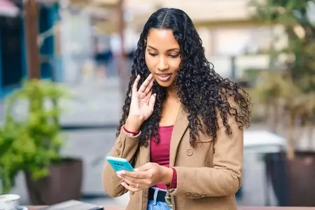 A young woman enjoys the outdoors while engaged with her smartphone  creating a cheerful vibe