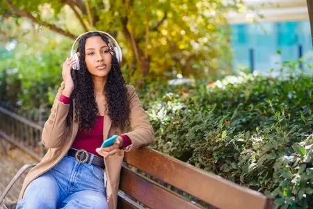 A Young Woman is Joyfully Enjoying Music While Outdoors in a Beautiful Park Setting