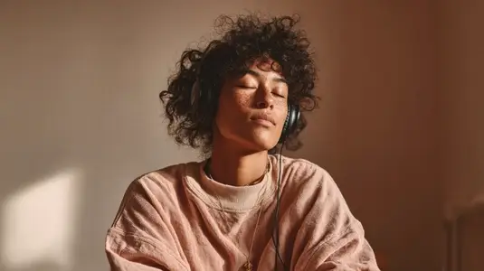 Person enjoying calming music with headphones  relaxed expression  cozy atmosphere  soft lighting  indoor setting