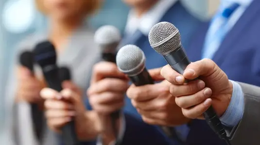 Journalists holding microphones during press conference  showcasing professional atmosphere and engagement with media