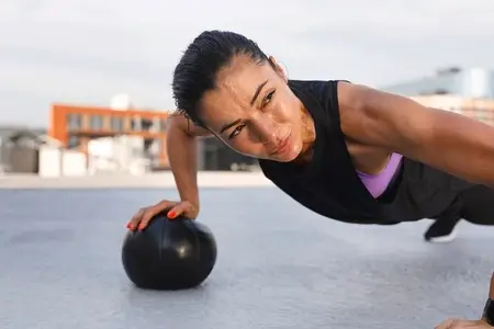Young woman doing intense strength workout on the roof  using medicine ball