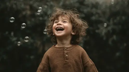 Joyful child laughing while playing with bubbles in natural outdoor setting  capturing essence of childhood happiness