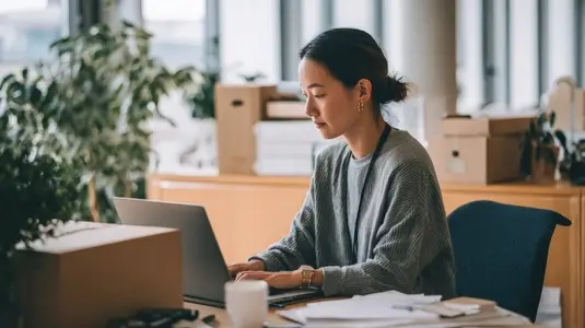 Focused employee working desk  setting up workspace with laptop  papers  and plants around  atmosphere is calm and productive
