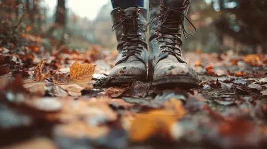 Close up of boots walking on fallen leaves in forest  showcasing autumn colors and sense of adventure