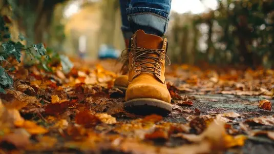 Close up of boots walking on fallen leaves  showcasing autumn colors and serene outdoor atmosphere