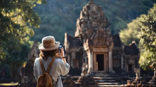 Traveler taking photo of ancient temple surrounded by nature  capturing memories in serene atmosphere