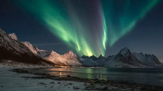 Northern lights illuminate night sky over snow covered mountains and calm lake creating breathtaking natural spectacle Northern lights illuminate night sky over snow covered mountains and calm lake creating breathtaking natural spectacle