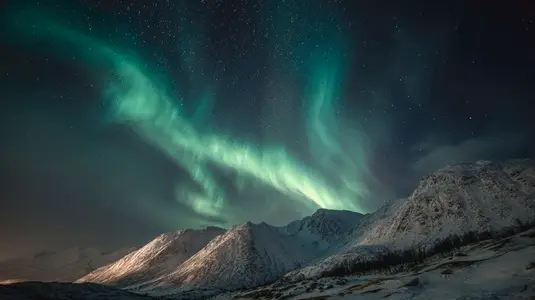 Northern lights illuminate night sky over snow covered mountains creating breathtaking and serene atmosphere Northern lights illuminate night sky over snow covered mountains creating breathtaking and serene atmosphere